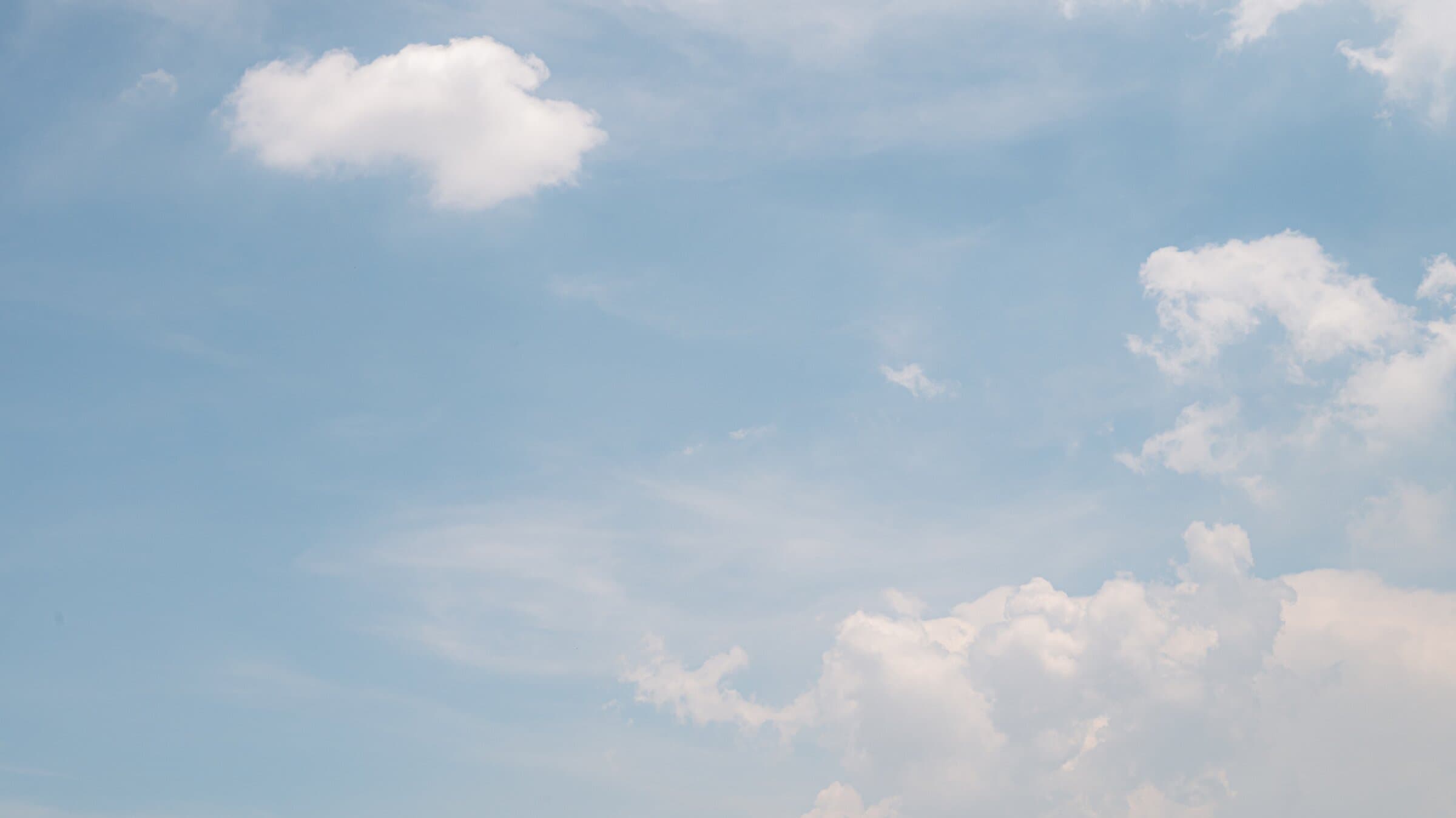 Soft cumulus clouds drifting across a bright blue sky