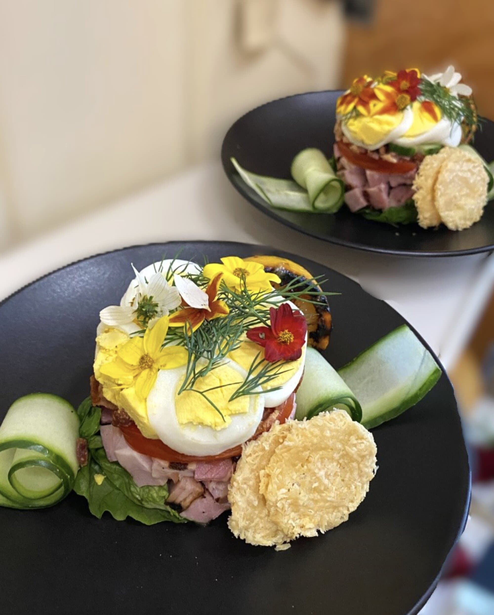 Stacked egg and cucumber composition garnished with edible flowers