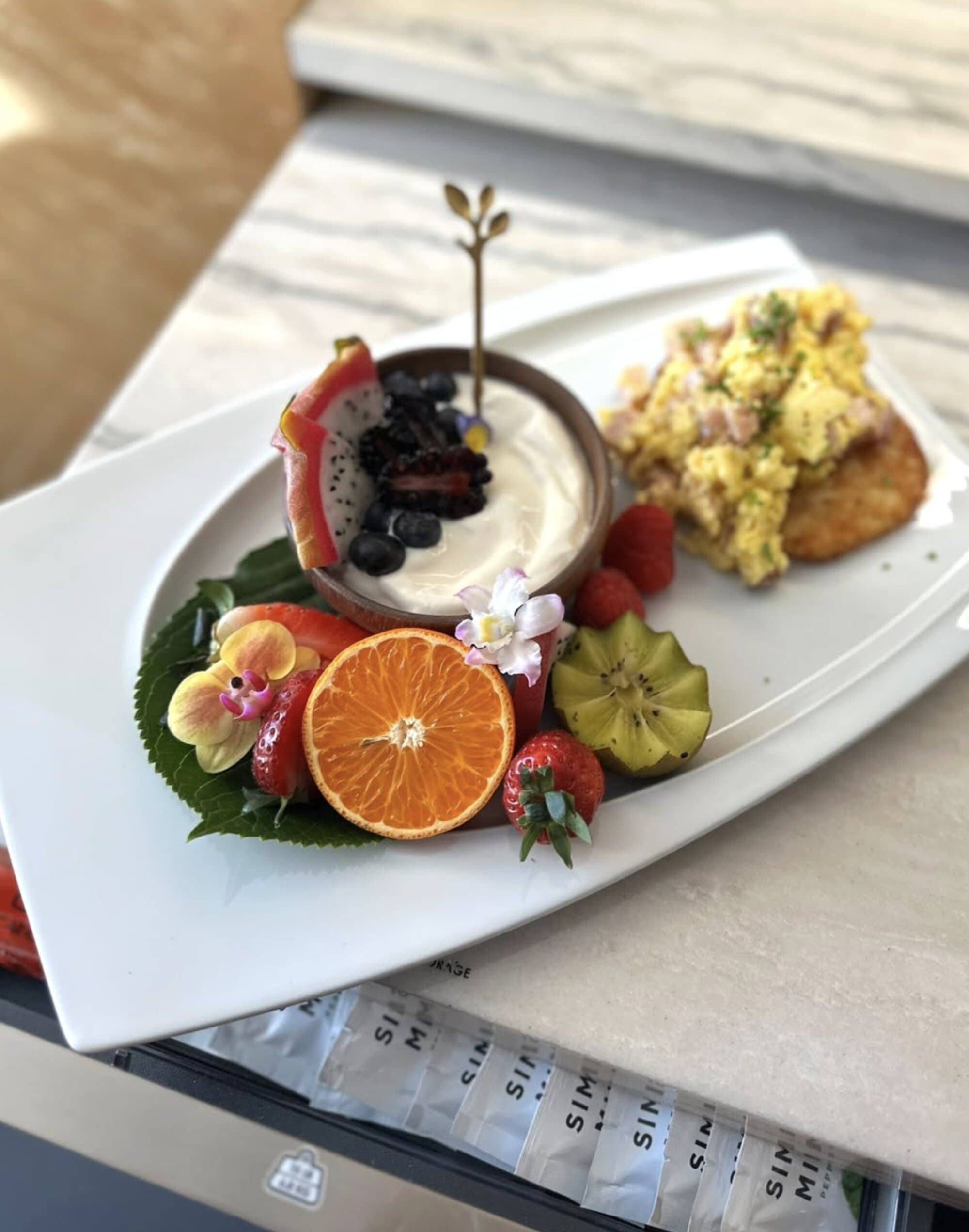 Breakfast plate with scrambled eggs, fresh fruit, and yogurt